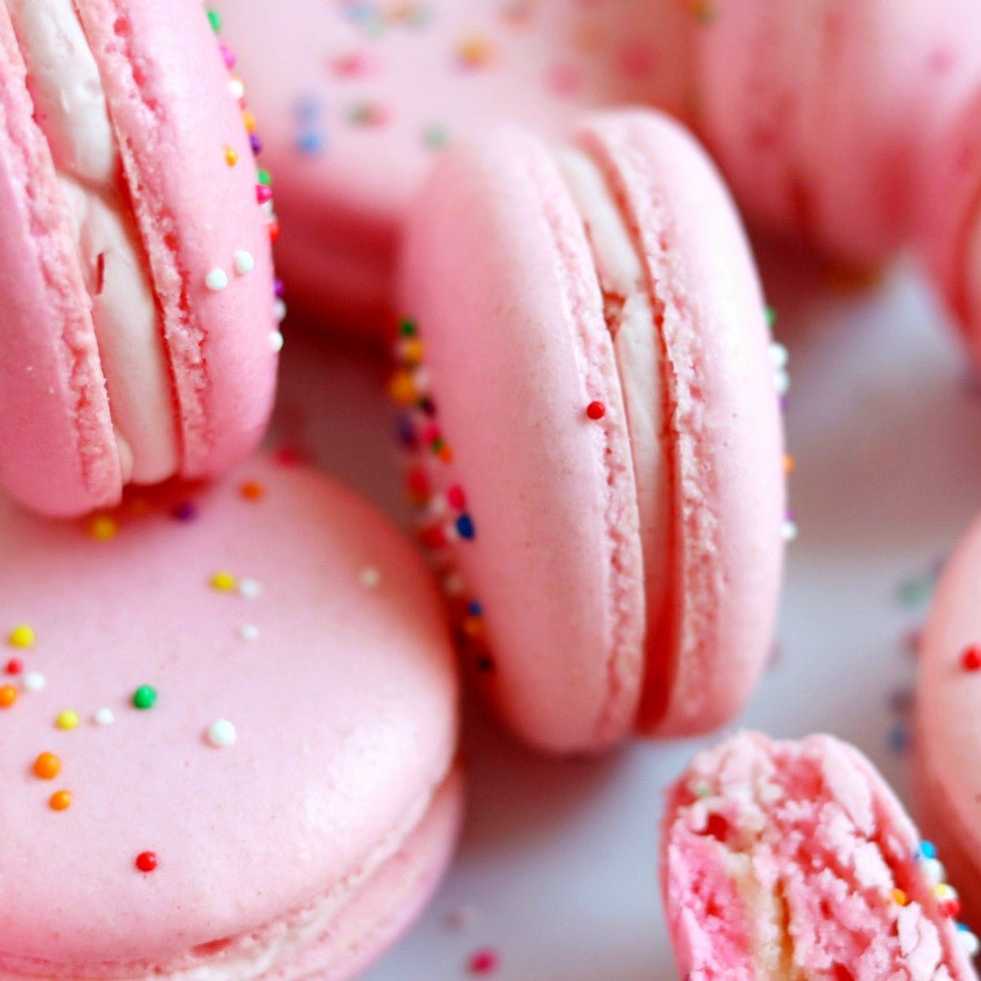 Macarons topped with colorful sprinkles and filled with cake batter buttercream.
